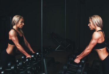 woman lifting weights while looking into a mirror