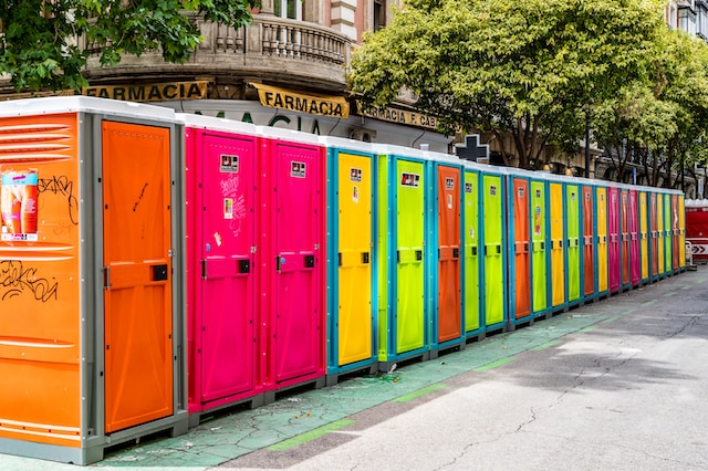 a row of multi-colored porta potties along a street