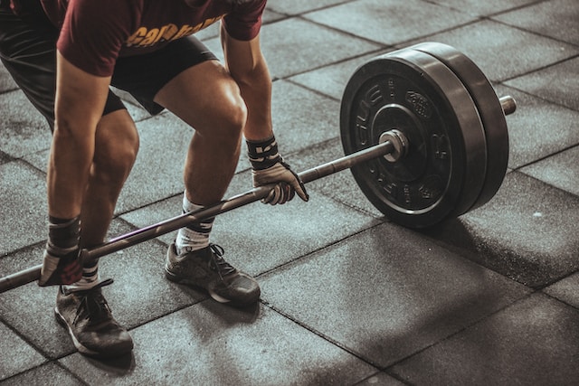 man squatting down to lift a barbell with weights