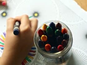 child with a jar of crayons doing a coloring page project