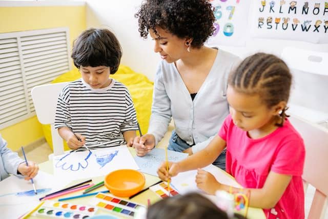 A teacher working with students as they paint with water colors