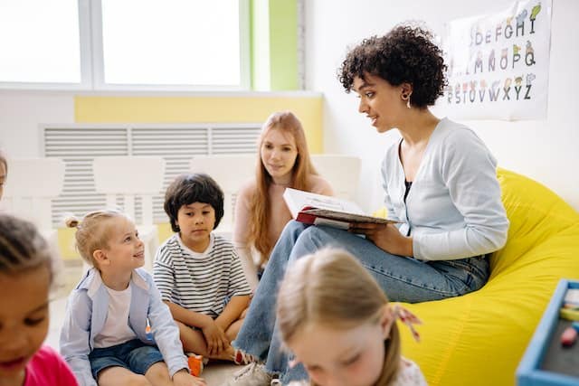 a teacher reading a book to her class of small children
