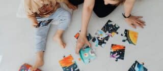 mother and child playing with a puzzle on the floor