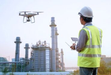 man using a drone to inspect large industrial towers