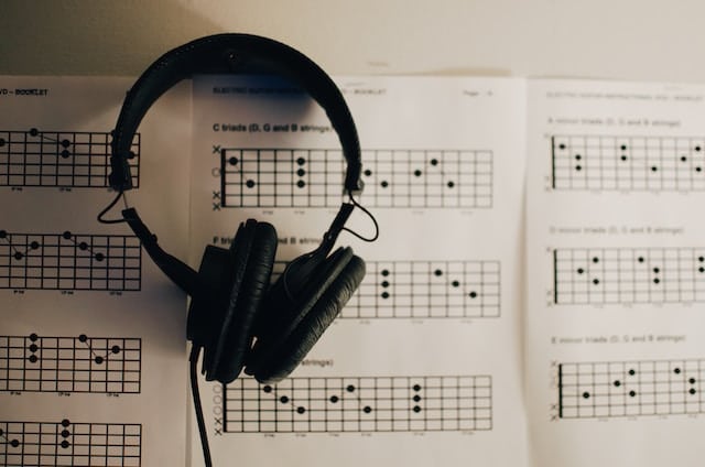 headphones sitting on top of guitar chord teaching sheets