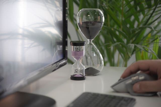 two hourglasses next to a computer monitor