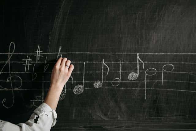 music teacher writing musical notes on a chalkboard