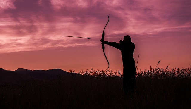 man hunting at sunset with bow and arrow