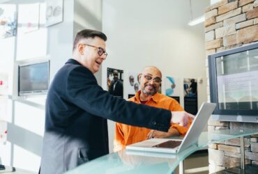 two men in a small business working on a laptop together.