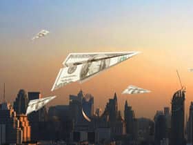 dollar bills folded into paper airplanes and flying above city skyline