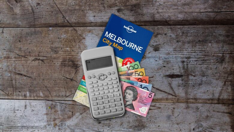 map of melbourne, australia and a calculator and money, laying on a table.