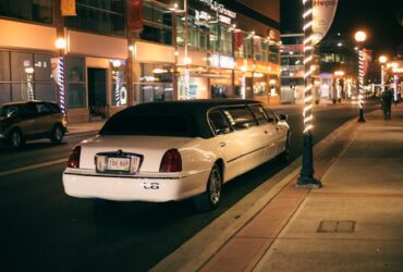 white limo parked on a city street at night.