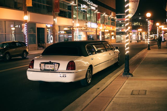 white limo parked on a city street at night.