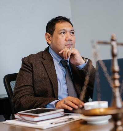 Asian male judge sitting at a table with scales of justice in the foreground