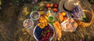 Picnic food with wine in a lavender field, vegetables and fruits