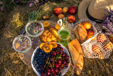 Picnic food with wine in a lavender field, vegetables and fruits