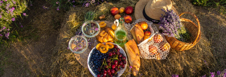 Picnic food with wine in a lavender field, vegetables and fruits