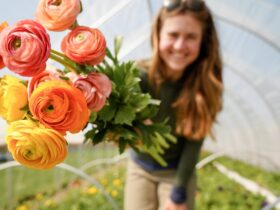 woman showing flowers grown in her greenhouse.