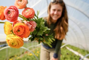 woman showing flowers grown in her greenhouse.