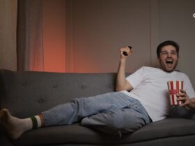 man laying on couch watching sports