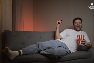 man laying on couch watching sports