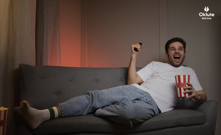 man laying on couch watching sports