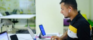 Man working on a laptop in an open office.