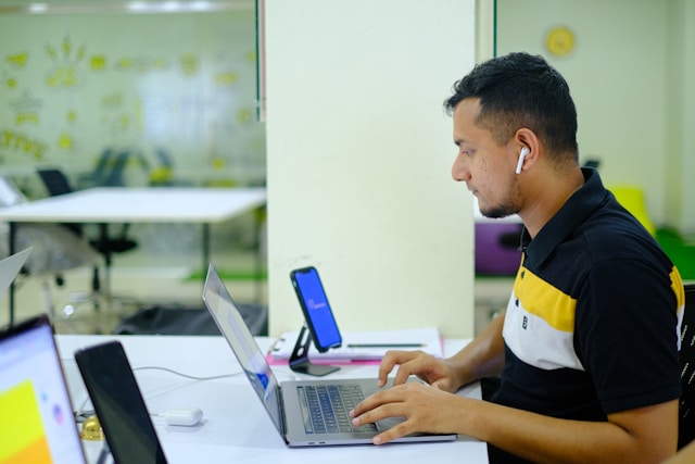 Man working on a laptop in an open office.