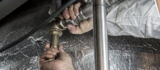 plumber fixing pipes under a counter.