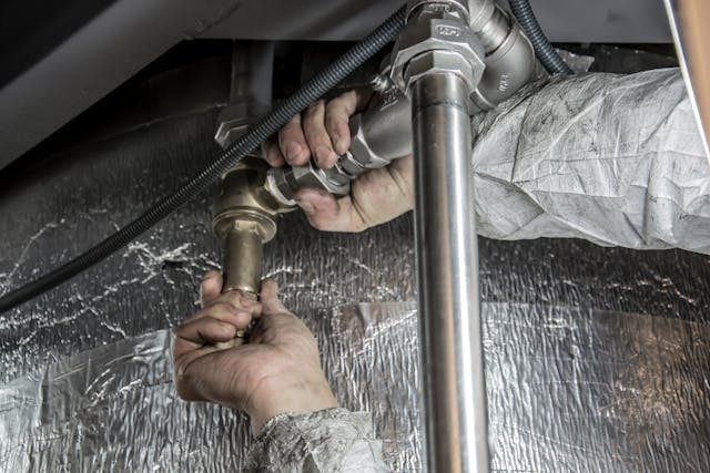 plumber fixing pipes under a counter.