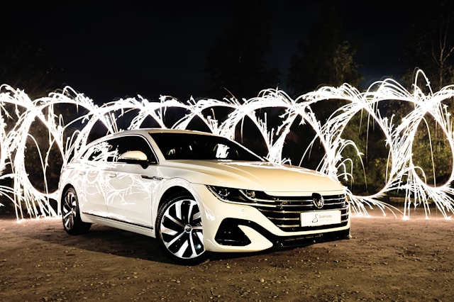 new, white sedan in front of a backdrop of sparkling lights.