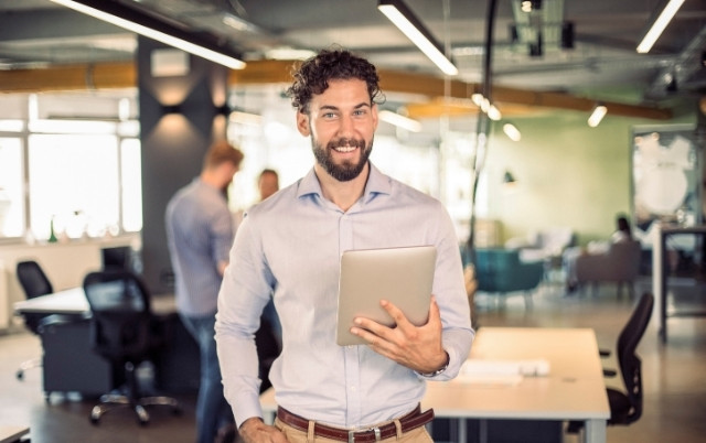 smiling man holding a tablet.