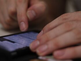 closeup of a man's hands reviewing texts on his phone.