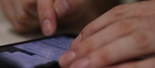 closeup of a man's hands reviewing texts on his phone.