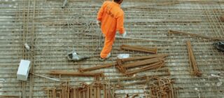 man walking over rebar at a construction site.