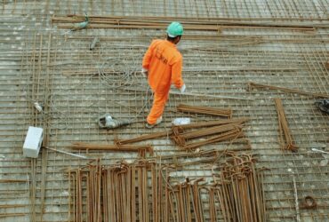 man walking over rebar at a construction site.