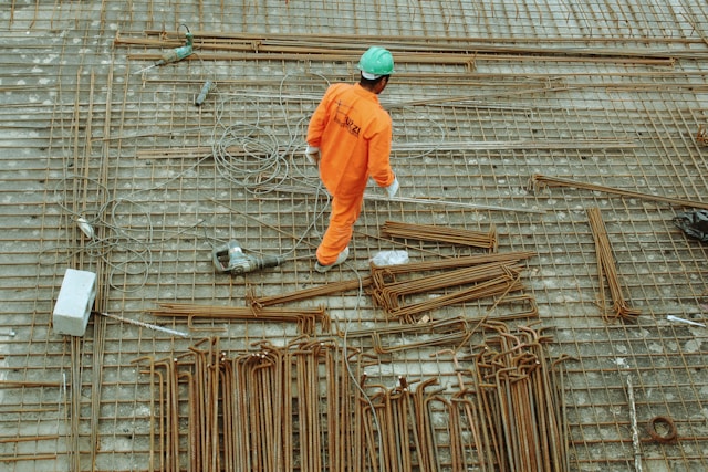 man walking over rebar at a construction site.