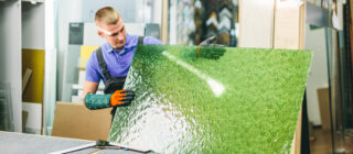 worker holding green glass pane
