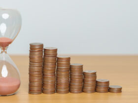 Stacks of coins next to hourglass