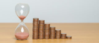 Stacks of coins next to hourglass