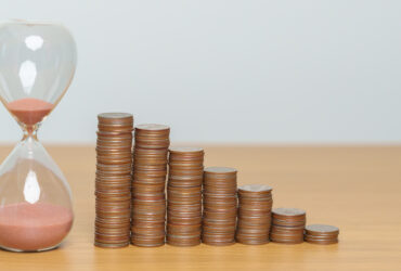 Stacks of coins next to hourglass