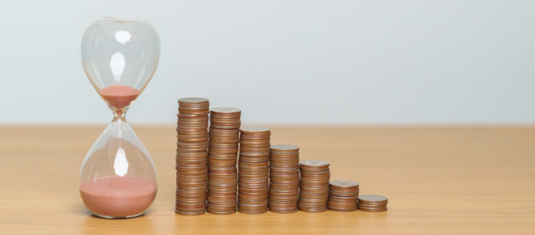 Stacks of coins next to hourglass