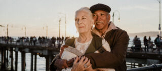 elderly couple by the sea embracing