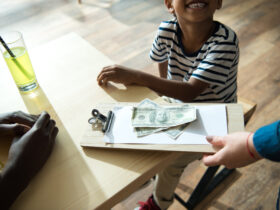 clipboard with money and paper on it and little kid looking up at person holding it
